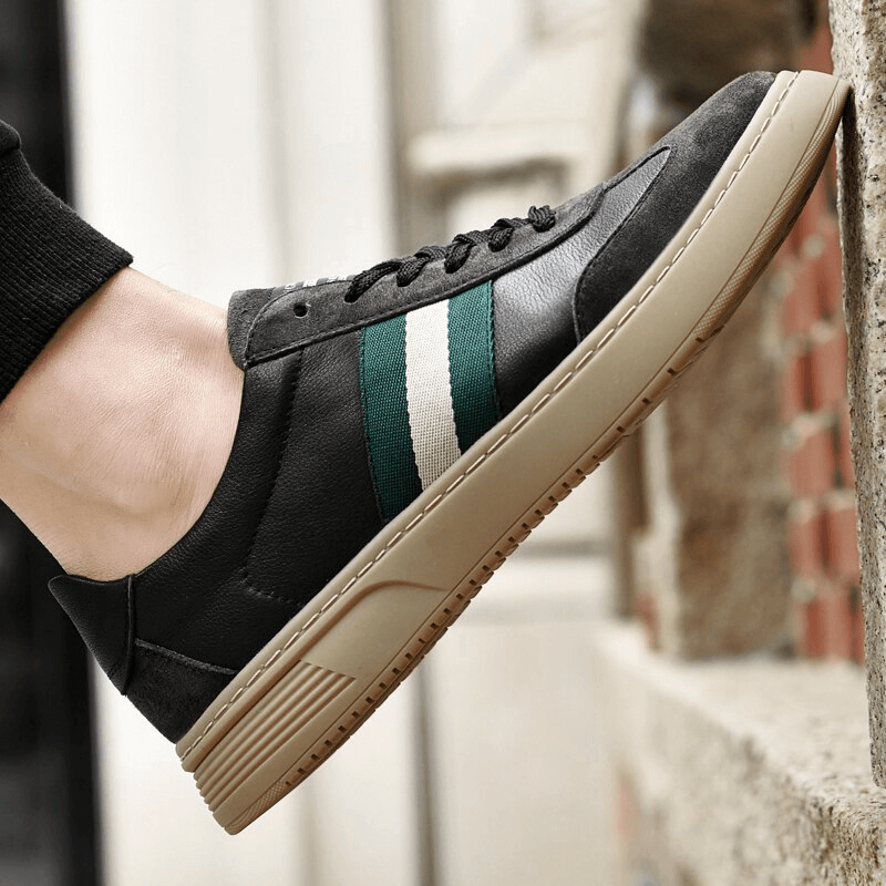 Black genuine leather men's sports-style shoe SF1176 with green stripe by a brick wall, showing durable rubber outsole detail.